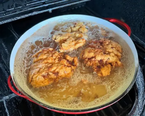 KFC Nashville Hot Chicken Combos are Back in 2026 14 KFC Nashville Hot Tenders frying in a pot of bubbling hot oil until the breading is golden-brown and extra crunchy.