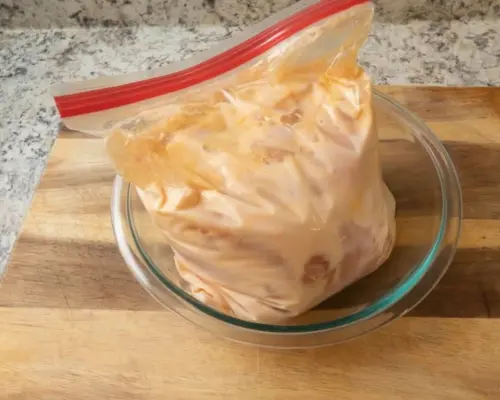 KFC Nashville Hot Chicken Combos are Back in 2026 12 Raw chicken pieces marinating in a resealable bag to develop the signature juicy flavor of KFC Nashville Hot Tenders.